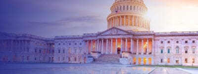 The U.S. Capitol building at sunset, with its prominent dome and neoclassical architecture, softly illuminated in the evening light.