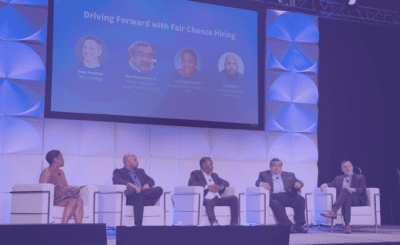 Five panelists seated on stage participate in a discussion titled 