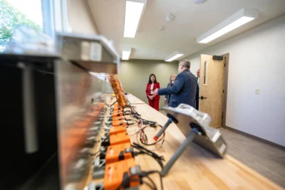 People discuss in a room with electronic devices on a long table.